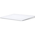 A sleek, white Apple Magic Trackpad with a large edge-to-edge glass surface and a low-profile ergonomic tilt, shown from a three-quarter perspective.