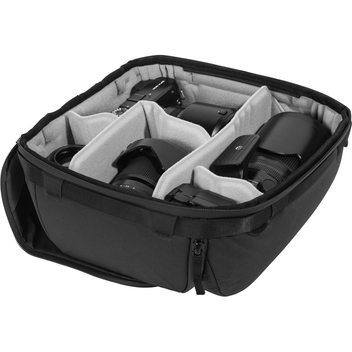 Black handheld Peak Design Camera Cube V2 with adjustable dividers, zipper closure, and durable nylon exterior, perfect for carrying camera gear safely.