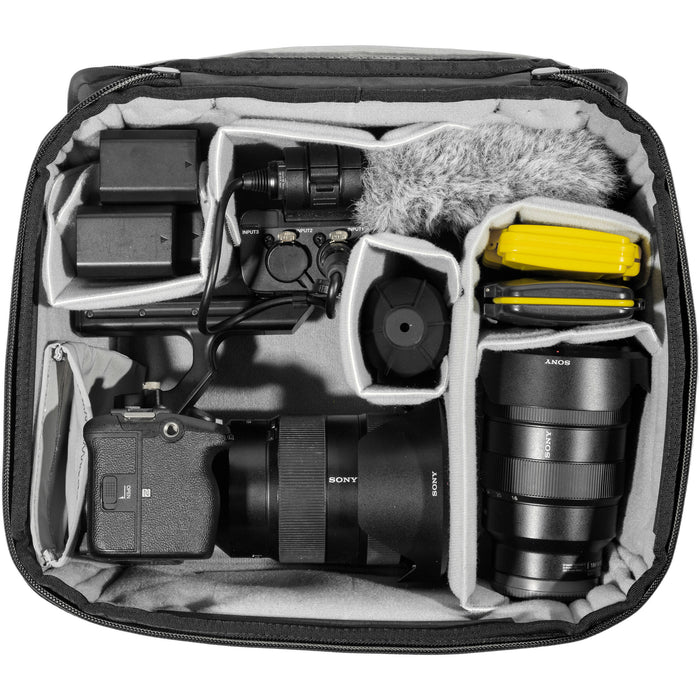 Black handheld Peak Design Camera Cube V2 with adjustable dividers, zipper closure, and durable nylon exterior, perfect for carrying camera gear safely.