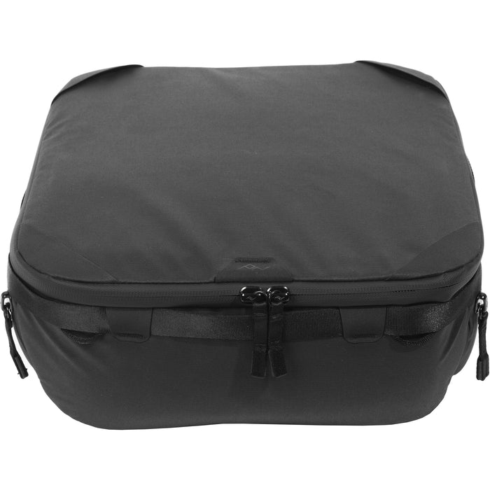 Black handheld Peak Design Camera Cube V2 with adjustable dividers, zipper closure, and durable nylon exterior, perfect for carrying camera gear safely.