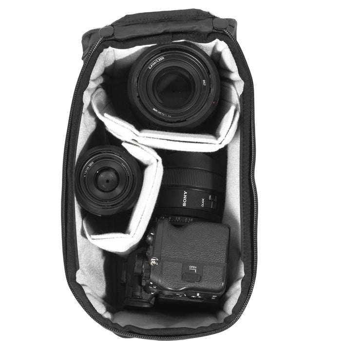 Black handheld Peak Design Camera Cube V2 with adjustable dividers, zipper closure, and durable nylon exterior, perfect for carrying camera gear safely.