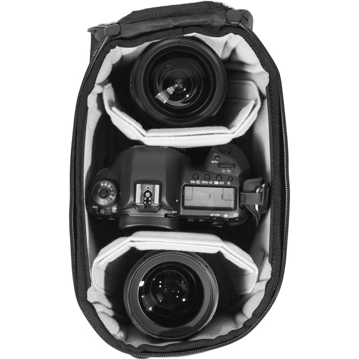 Black handheld Peak Design Camera Cube V2 with adjustable dividers, zipper closure, and durable nylon exterior, perfect for carrying camera gear safely.