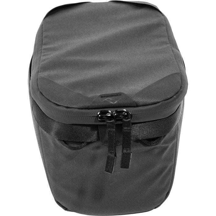 Black handheld Peak Design Camera Cube V2 with adjustable dividers, zipper closure, and durable nylon exterior, perfect for carrying camera gear safely.