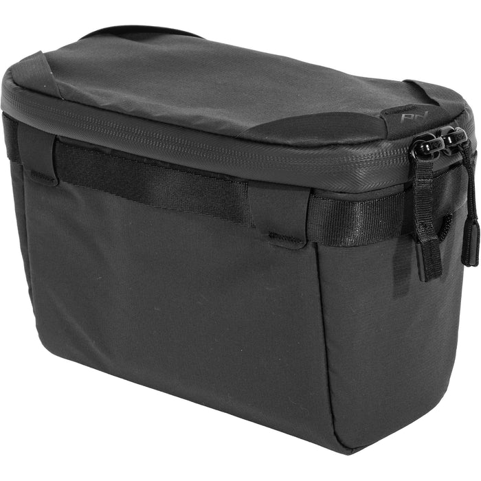 Black handheld Peak Design Camera Cube V2 with adjustable dividers, zipper closure, and durable nylon exterior, perfect for carrying camera gear safely.