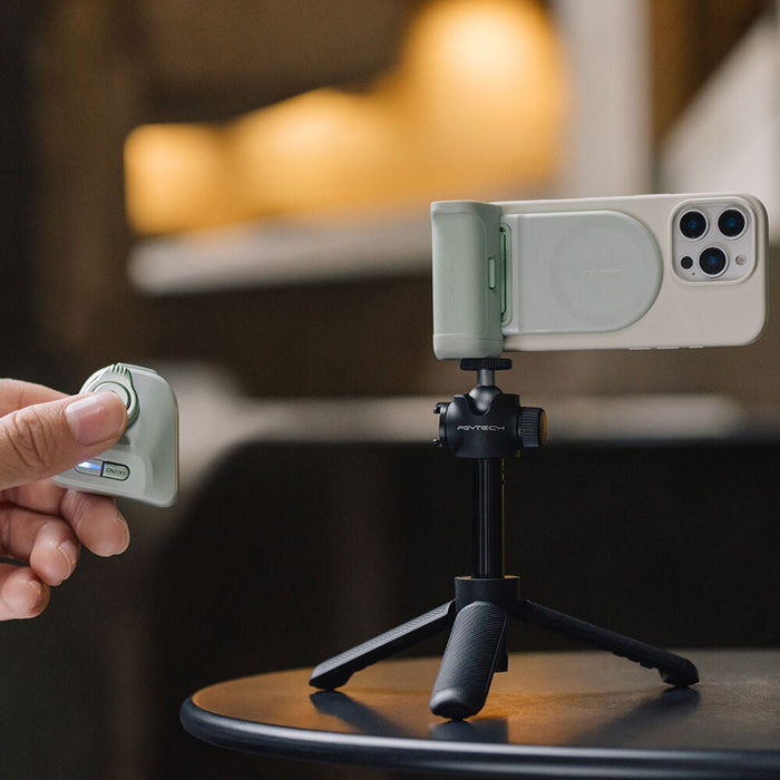 Hand holding a smartphone with a camera lens cover on a tripod, blurred background